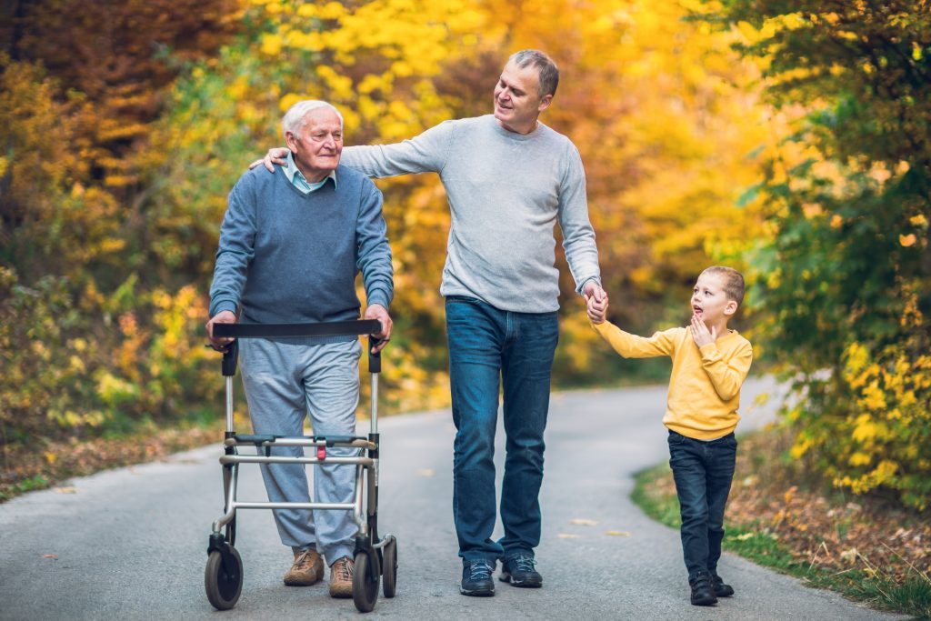 An elderly man with son and grandson on a walk