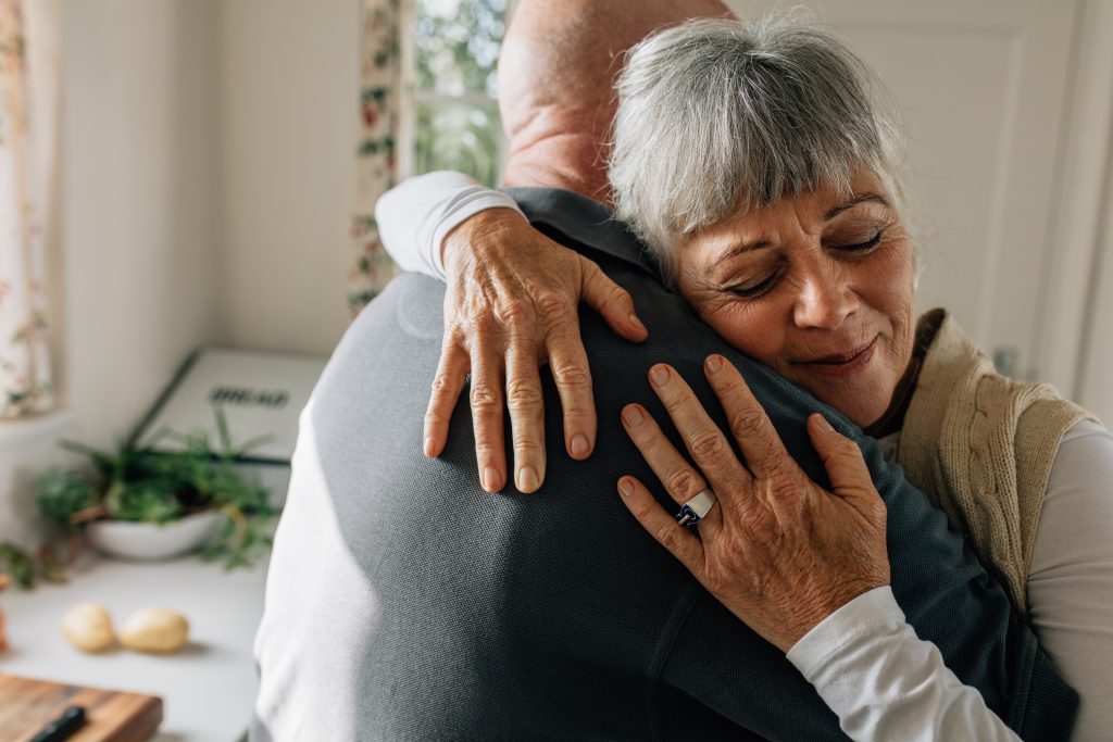 An elderly couple hugging