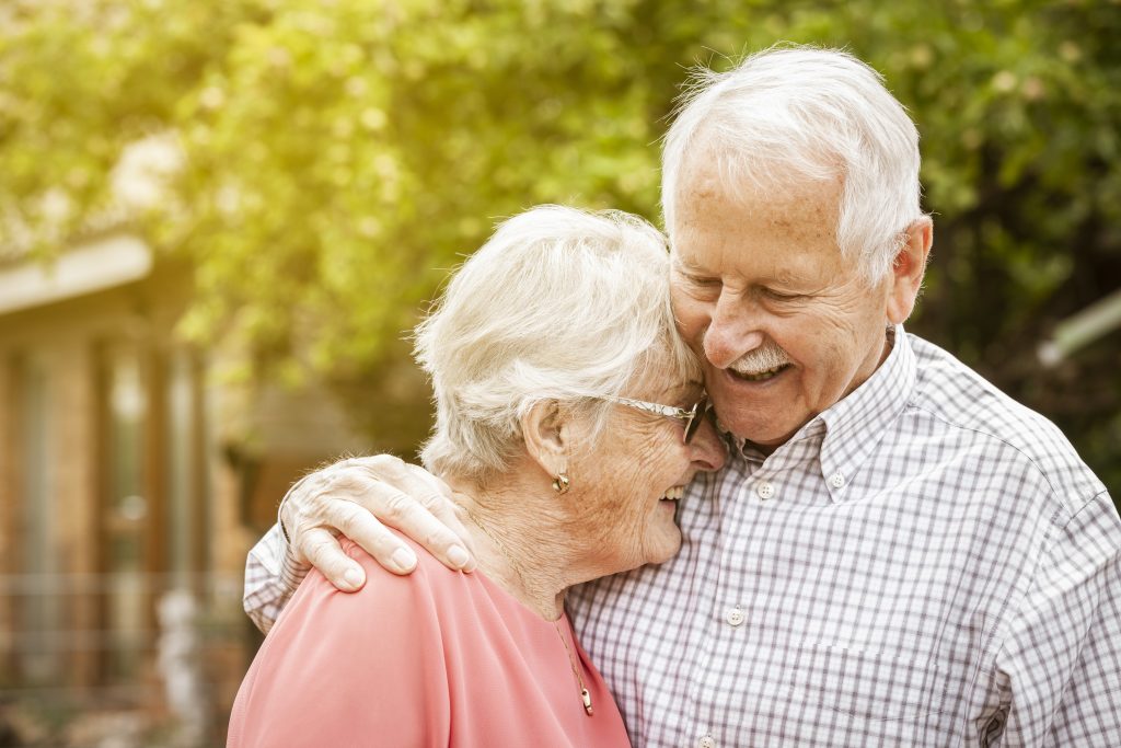 An elderly couple embracing happily
