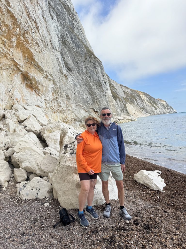 Paul and his wife standing in front of white cliffs next to the ocean. Part of a trip to see the Isle of Wight prostate cancer support group.